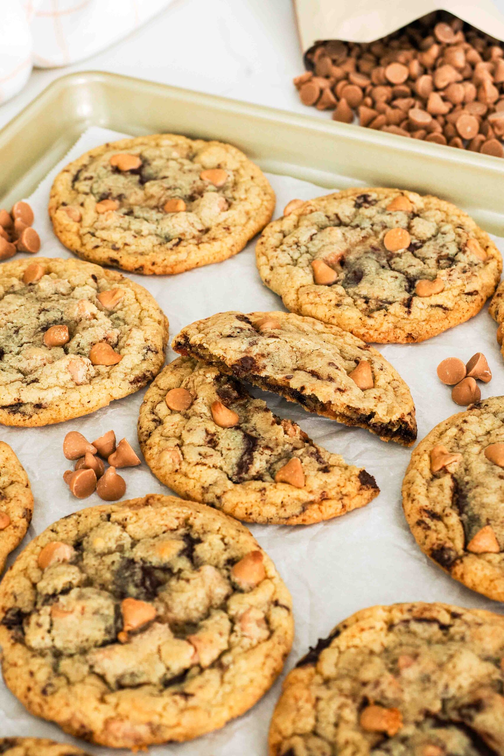 A caramel chocolate chip cookie is broken in half.