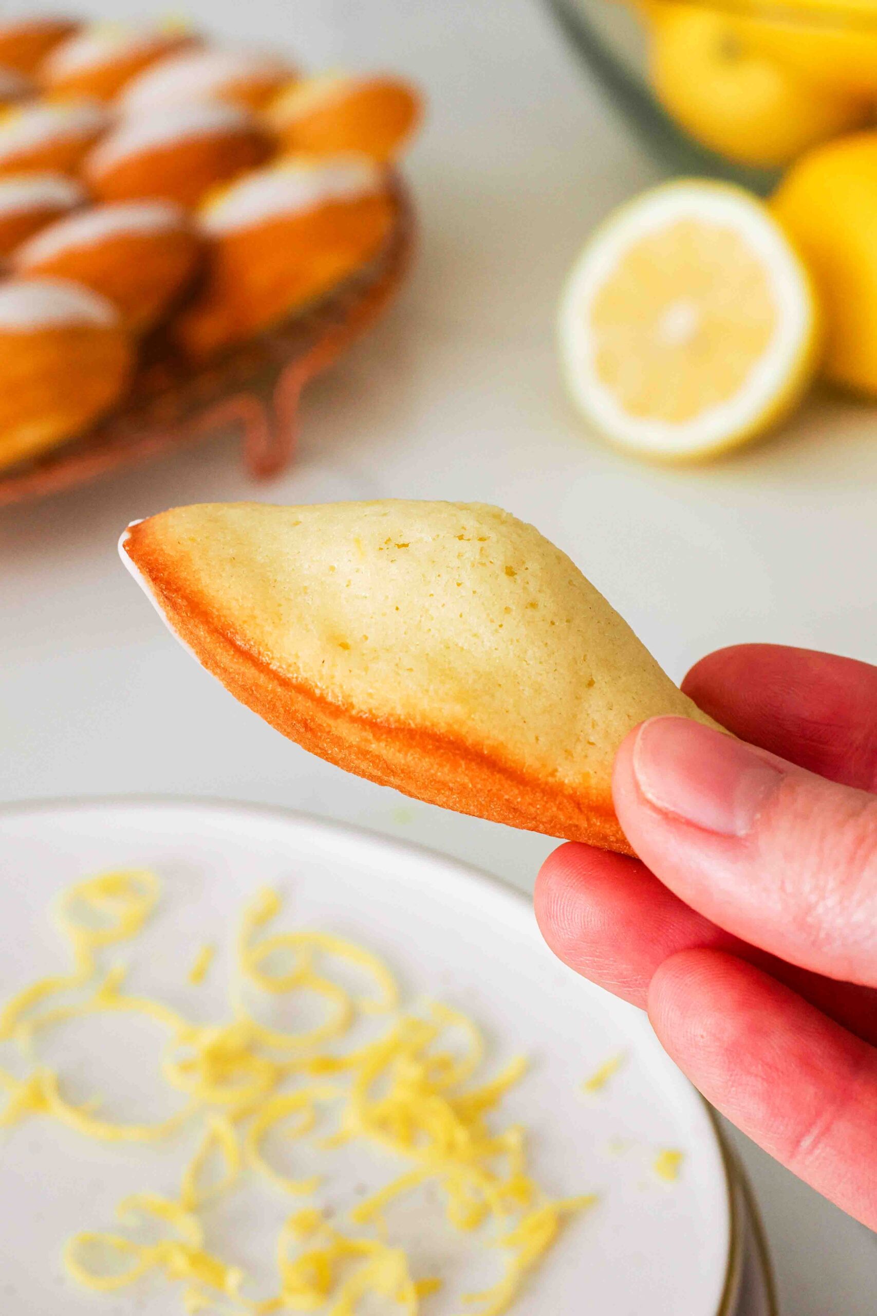 A lemon madeleine is flipped over to see the tall hump on the back.
