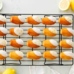 Dipped lemon madeleines on a wire cooling rack.