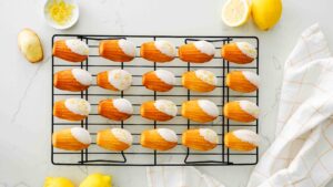 Dipped lemon madeleines on a wire cooling rack.