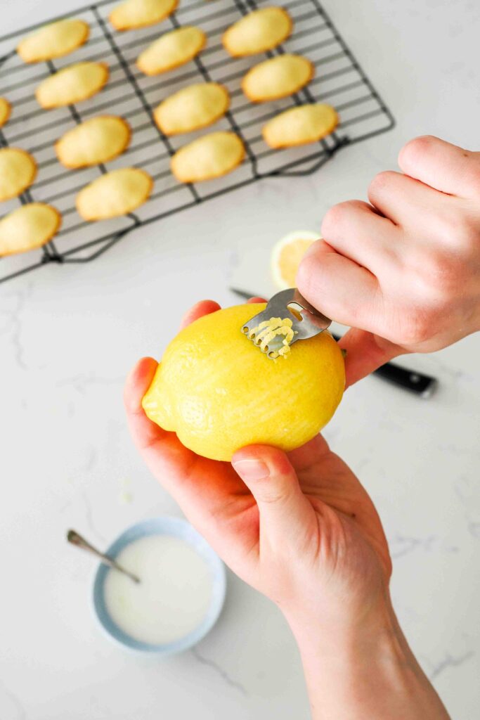 A lemon is peeled with a citrus zester for long strips of zest.