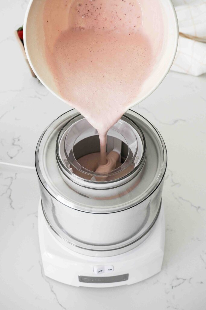 Strawberry custard is poured into an ice cream maker.