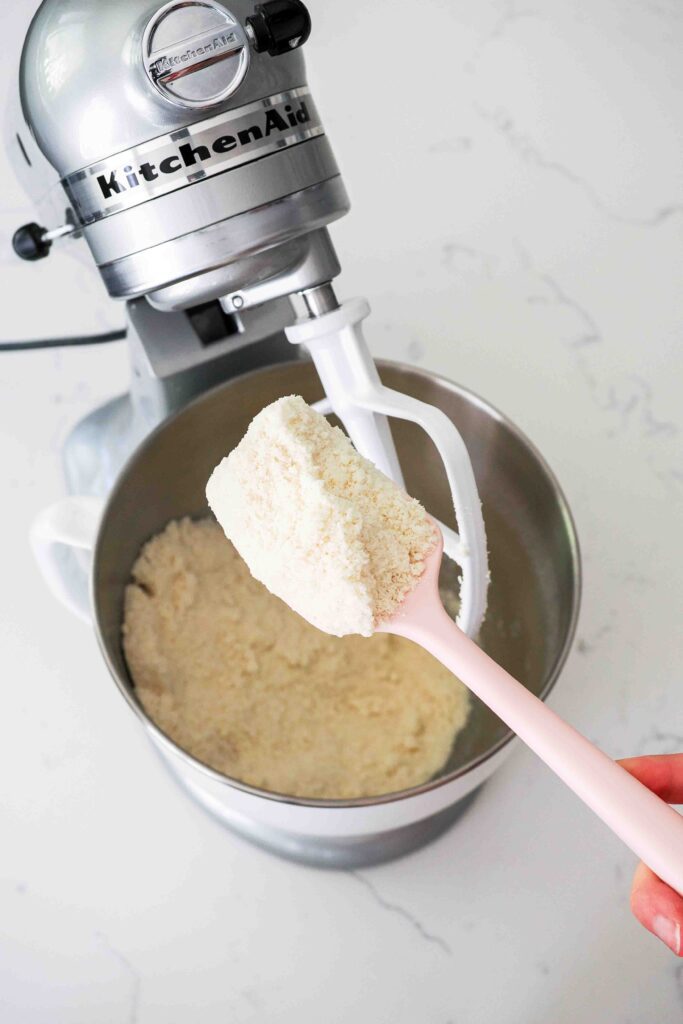 A spatula holds up the creamed butter, flour, and sugar mixture.