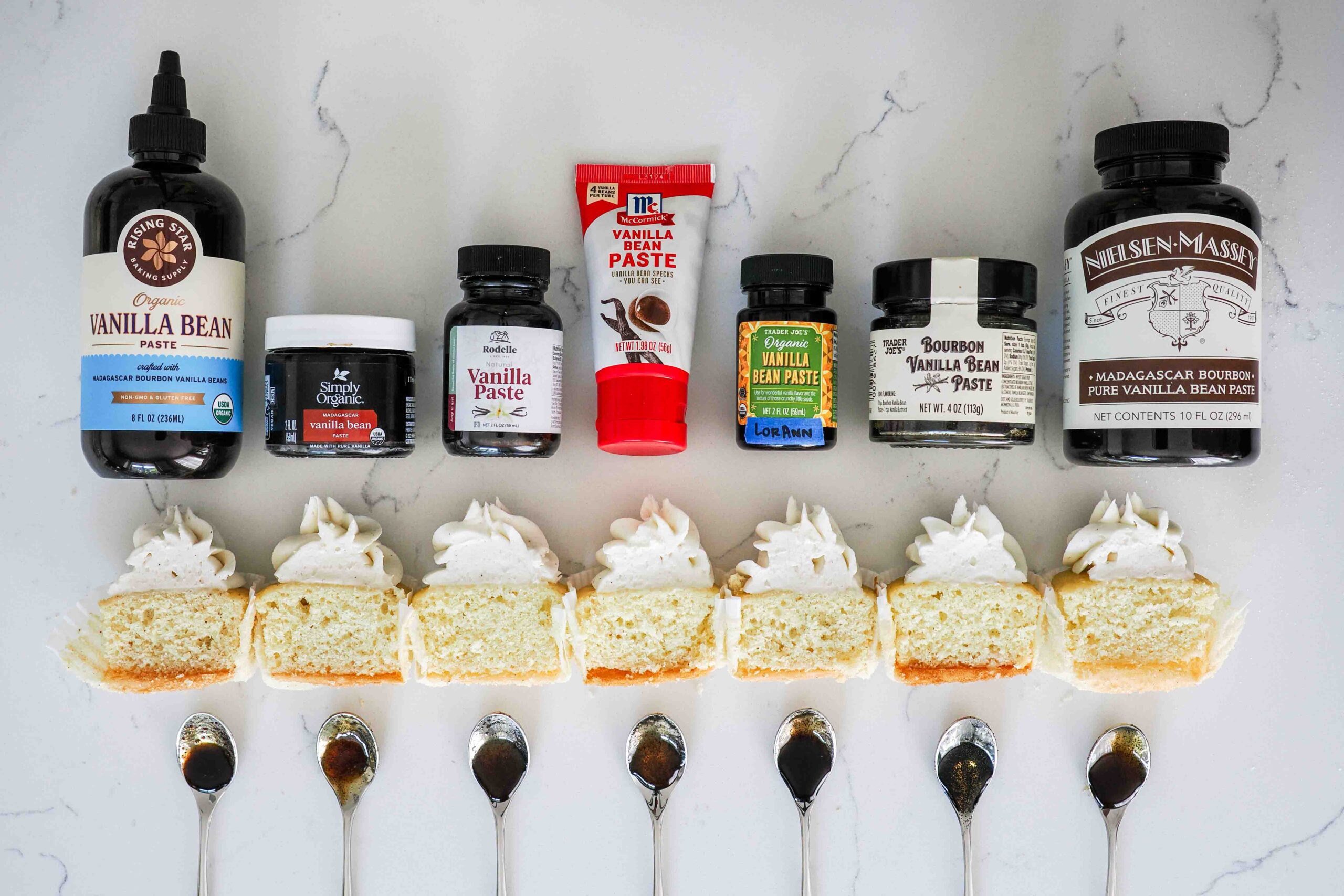 Vanilla bean pastes with half of a cupcake and sampling spoons under each.