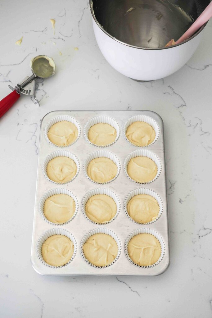 Unbaked vanilla bean cupcakes in a muffin pan.