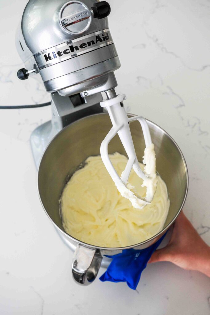 Butter is creamed until smooth in the bottom of a stand mixer bowl.