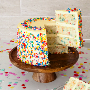 A slice of mini confetti cake is removed from a cake stand.