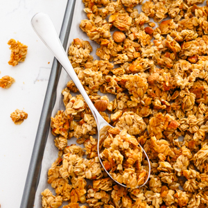 A spoon in a pan of vanilla almond granola.