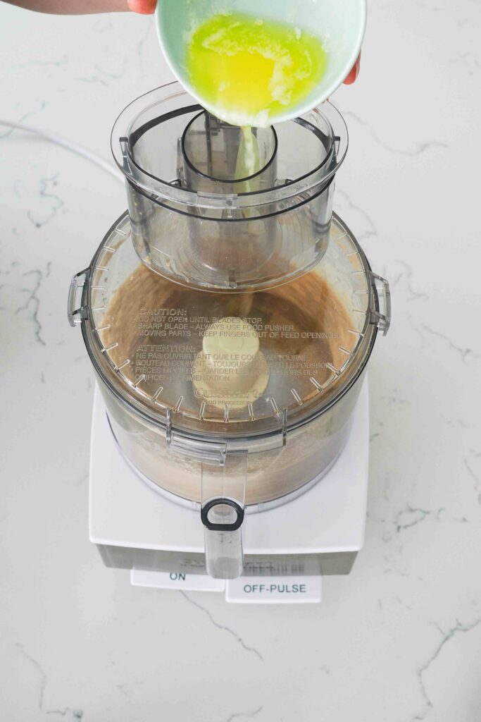 Melted butter is streamed into a food processor with crushed graham crackers.