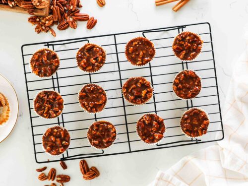 Mini pecan pie cheesecakes on a cooling rack.