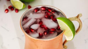 A closeup of a pomegranate Moscow mule in a copper mug.