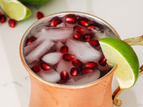 A closeup of a pomegranate Moscow mule in a copper mug.