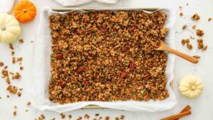 An overhead view of a pan of pumpkin granola on a quartz countertop.