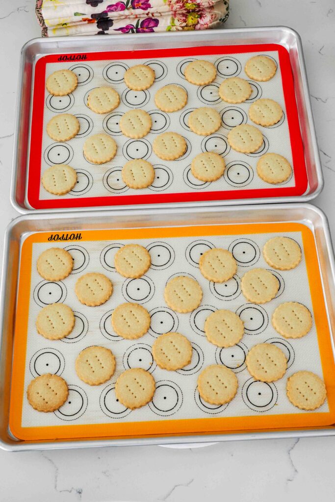 Baked vanilla shortbread cookies on baking mats.