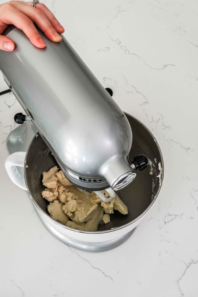 A stand mixer has beaten shortbread dough enough to make it hold together in the bowl.