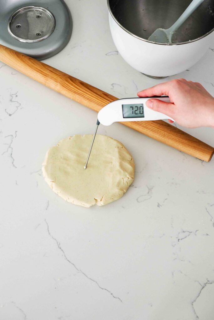 A digital thermometer reads 72°F when inserted into shortbread dough.