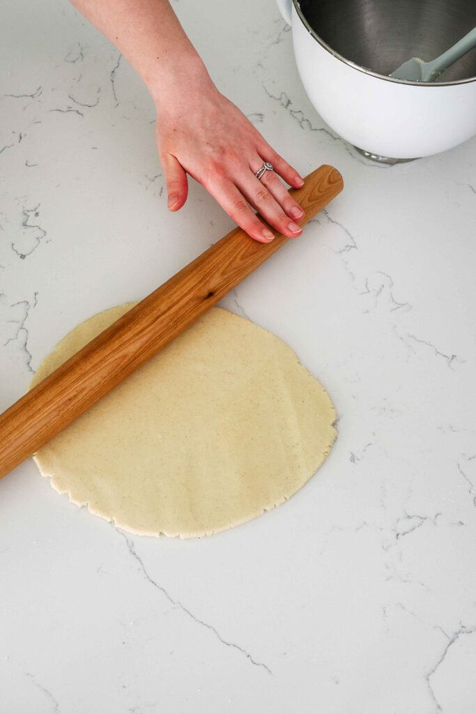 Shortbread dough is rolled out on a quartz counter.