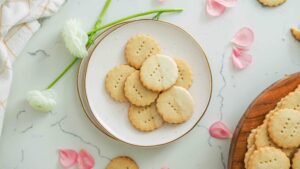 Vanilla shortbread cookies on a plate near flower petals.