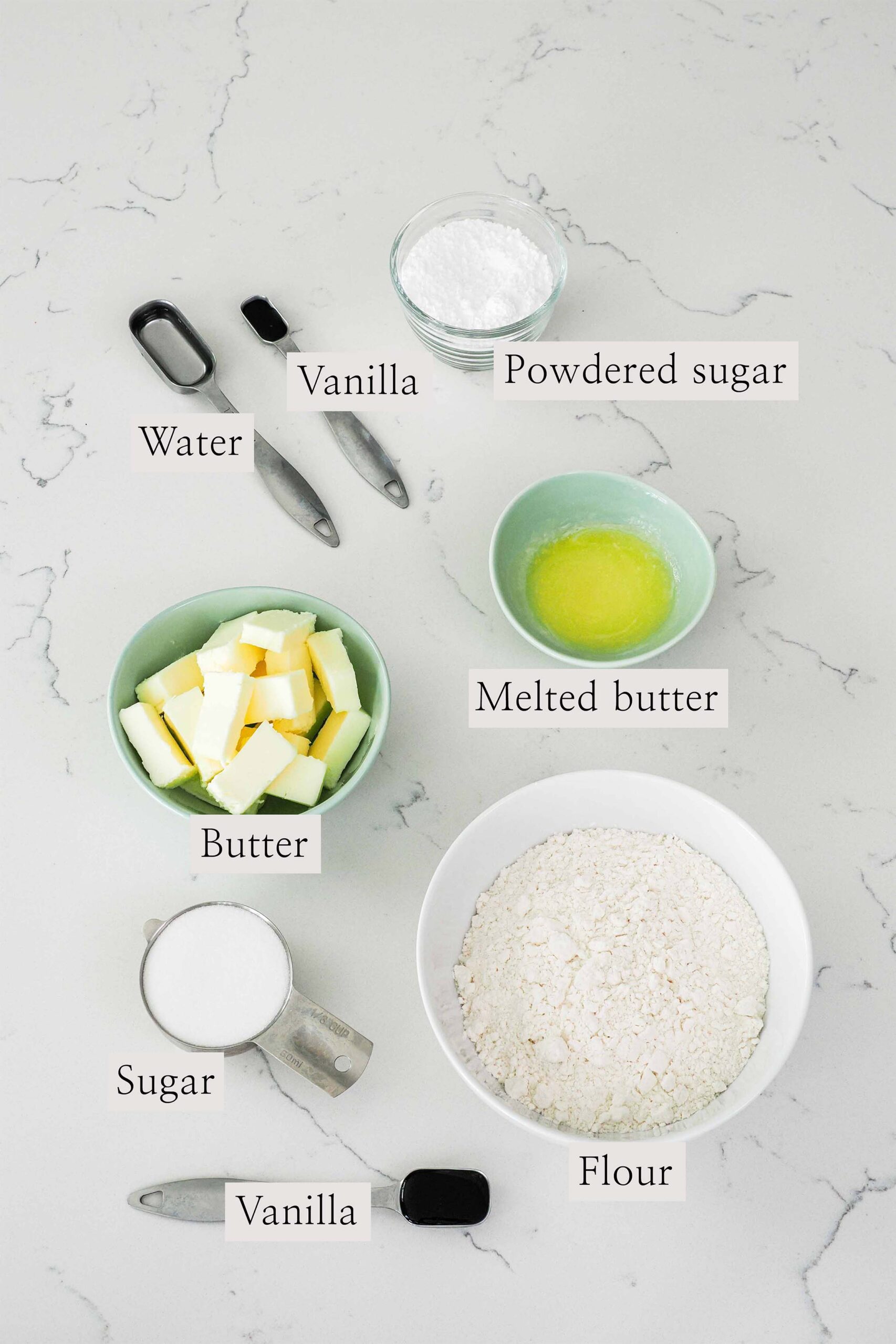 Ingredients needed to make vanilla shortbread cookies on a quartz counter.