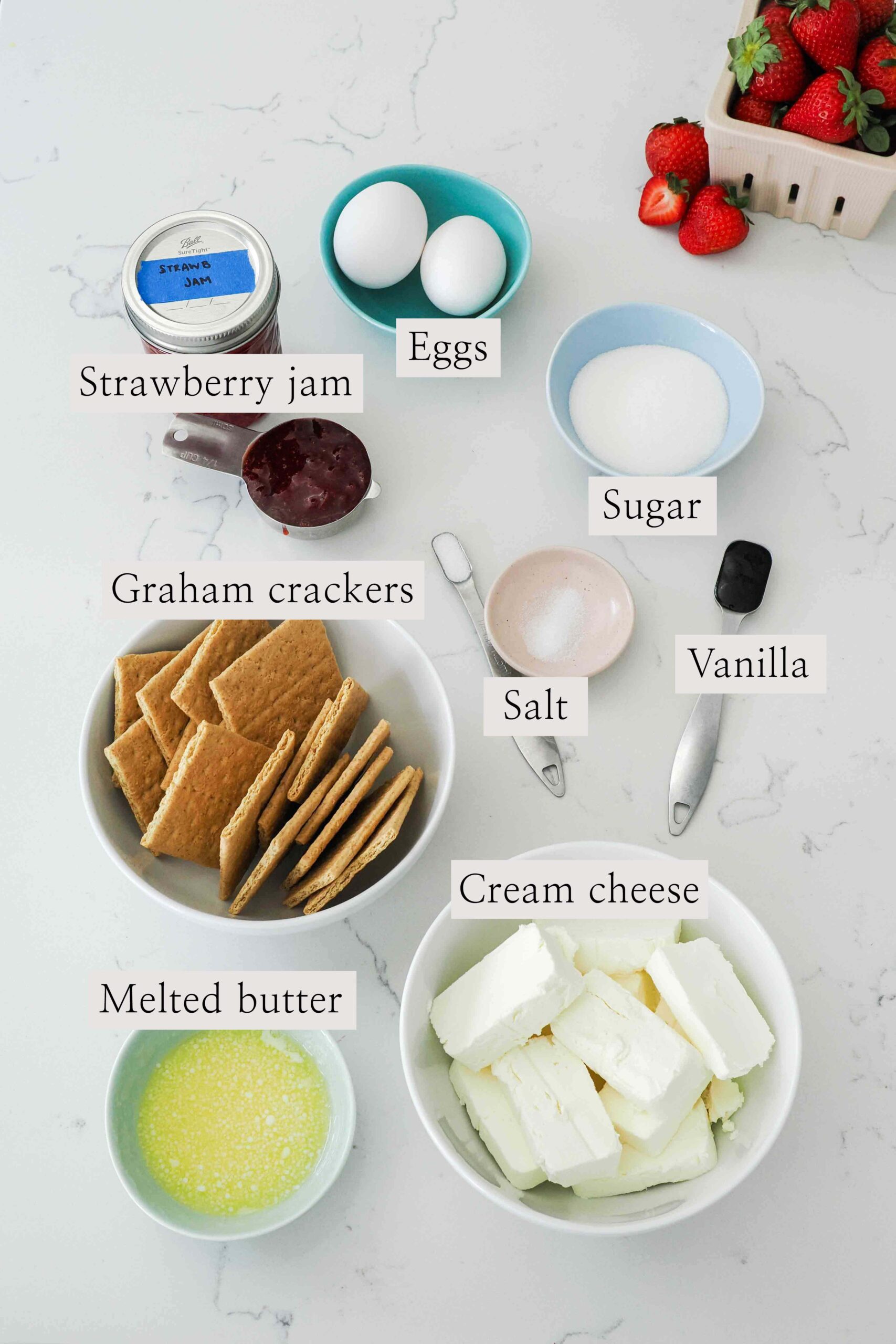Ingredients used to make mini strawberry cheesecakes on a counter.