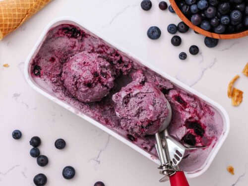 Two scoops of blueberry ice cream in a long ice cream container.