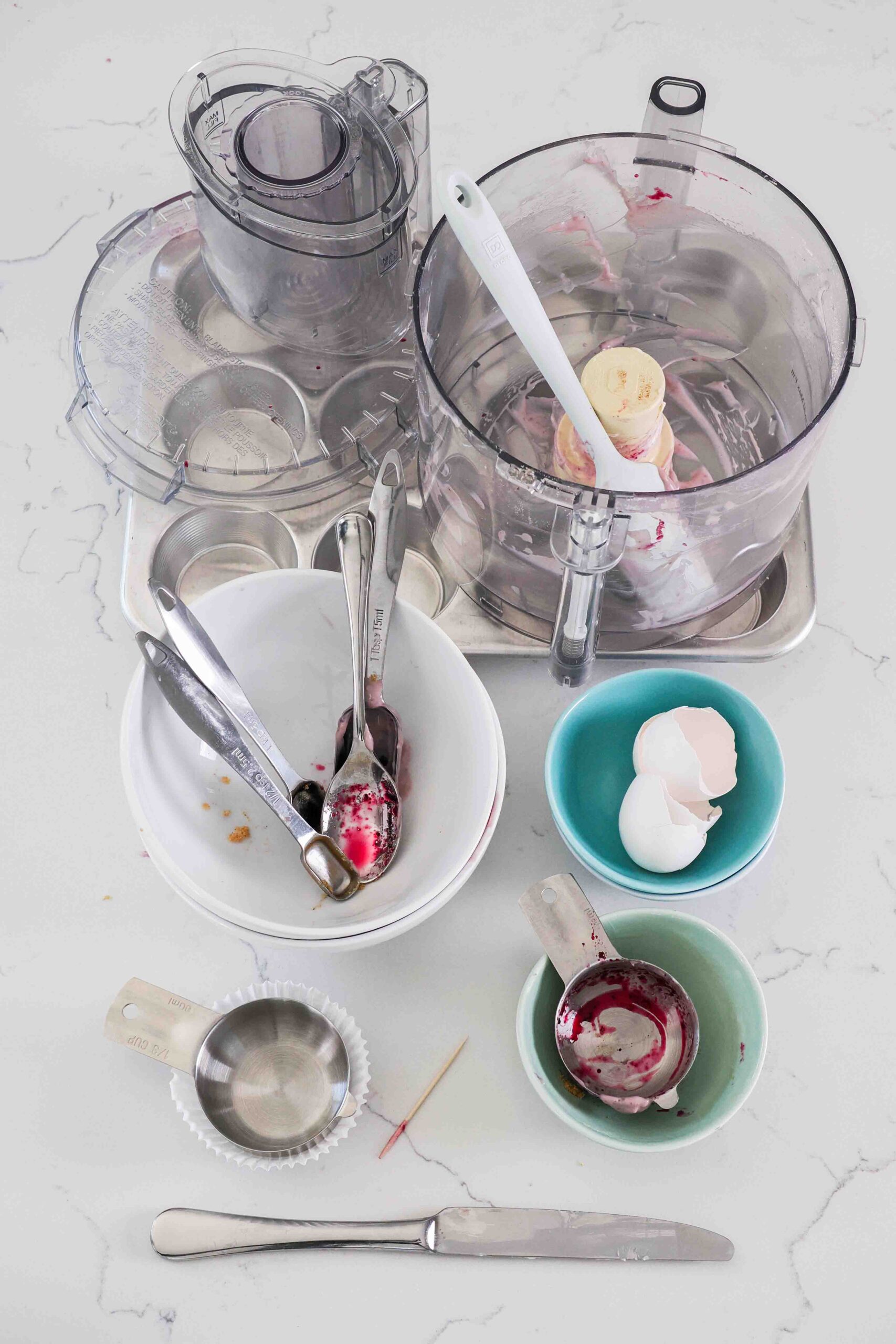 Dishes needed to make mini blueberry cheesecakes on a quartz counter.